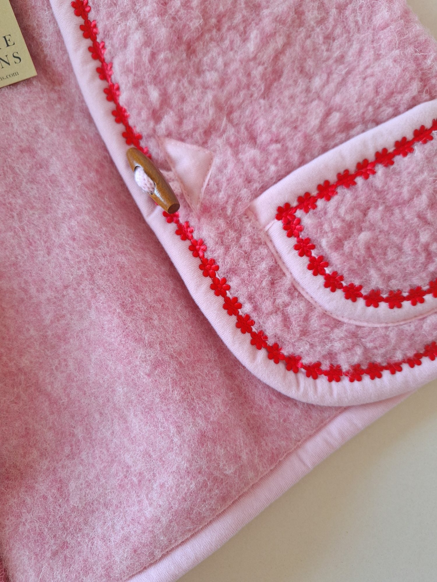 Close-up of the inside of a pink wool bodywarmer with red flower trim.