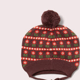 Knitted hat with floral pattern and pom-pom on a light gray background