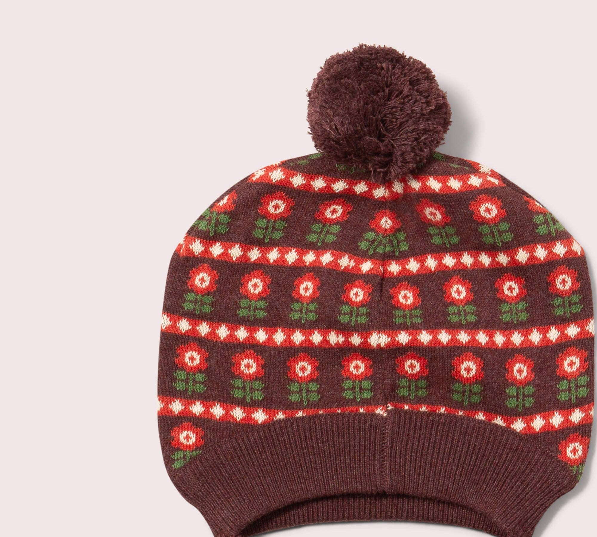 Knitted hat with floral pattern and pom-pom on a light gray background