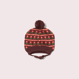 Knitted hat with a patterned top and brown brim on a light pink background