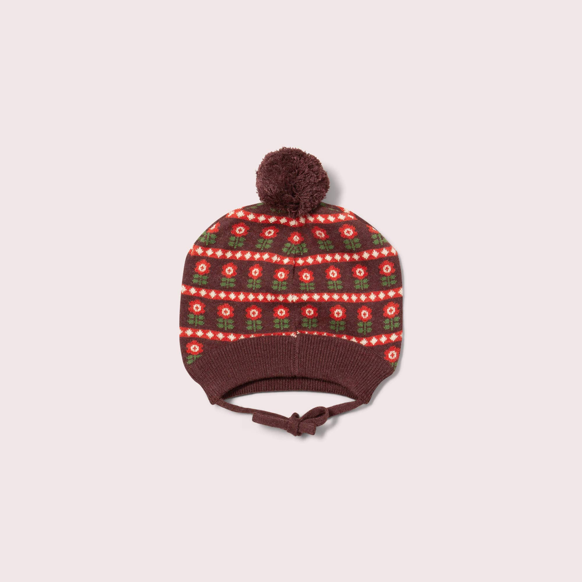 Knitted hat with a patterned top and brown brim on a light pink background
