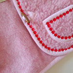 Close-up of the inside of a pink wool bodywarmer with red flower trim.